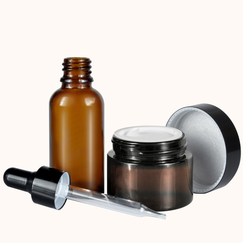 A set of frosted clear amber black personal skin care glass dropper bottles and glass jar
