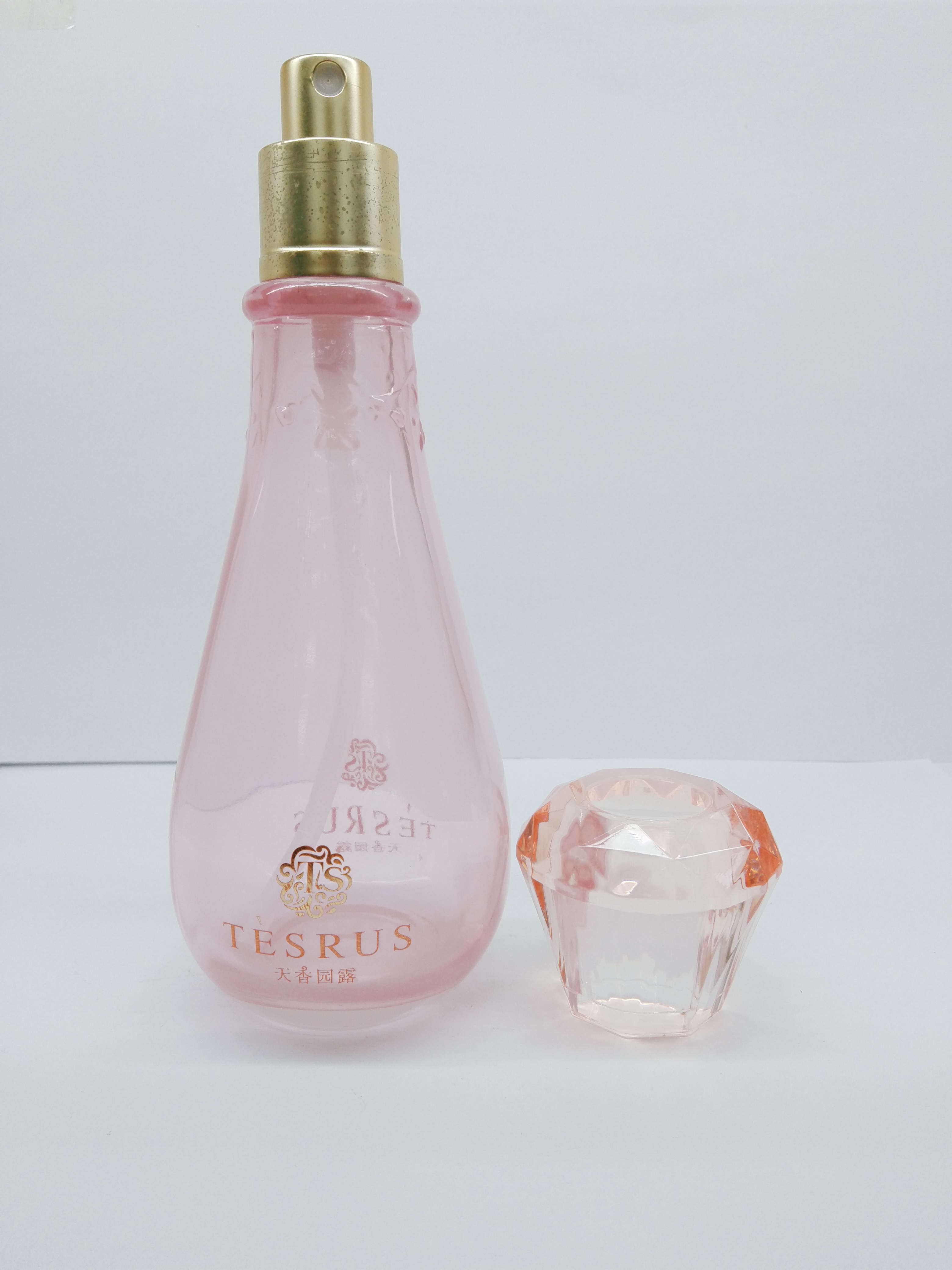 Clear pink color glass bottle with diamond-shaped cap