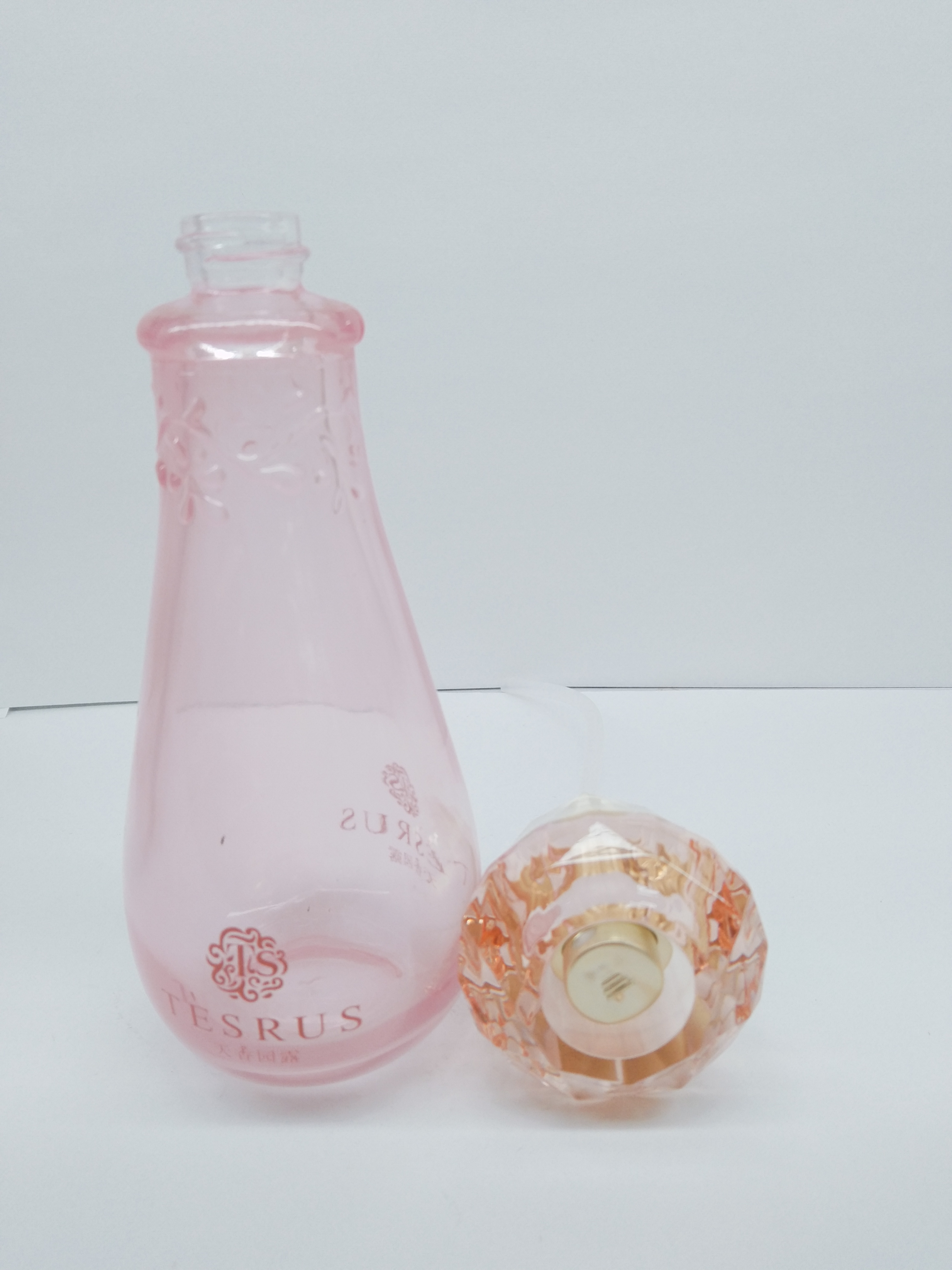 Clear pink color glass bottle with diamond-shaped cap