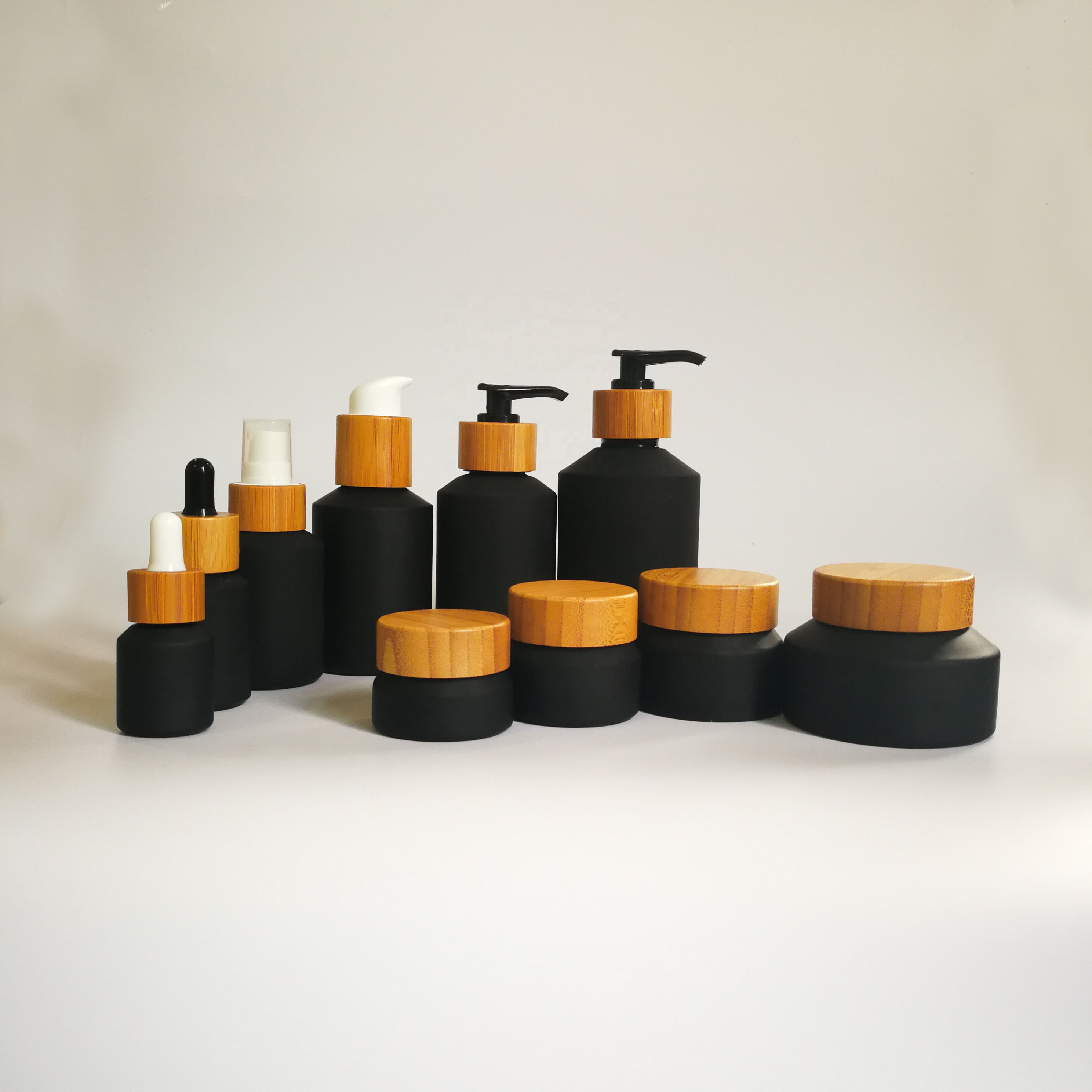 Cosmetic packaging slant shoulder matte black skin care set black glass bottle with bamboo dropper and bamboo cap jar