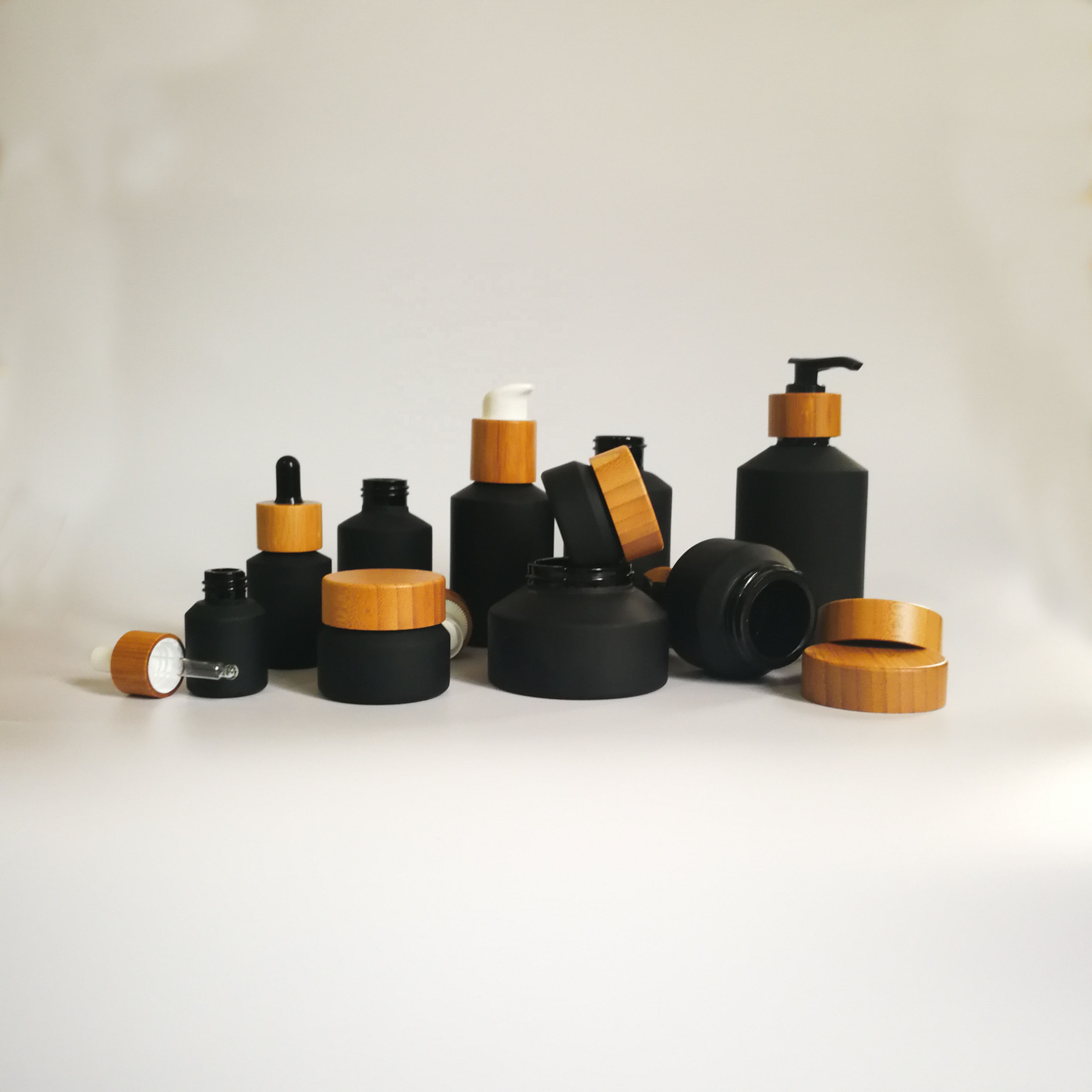 Cosmetic packaging slant shoulder matte black skin care set black glass bottle with bamboo dropper and bamboo cap jar