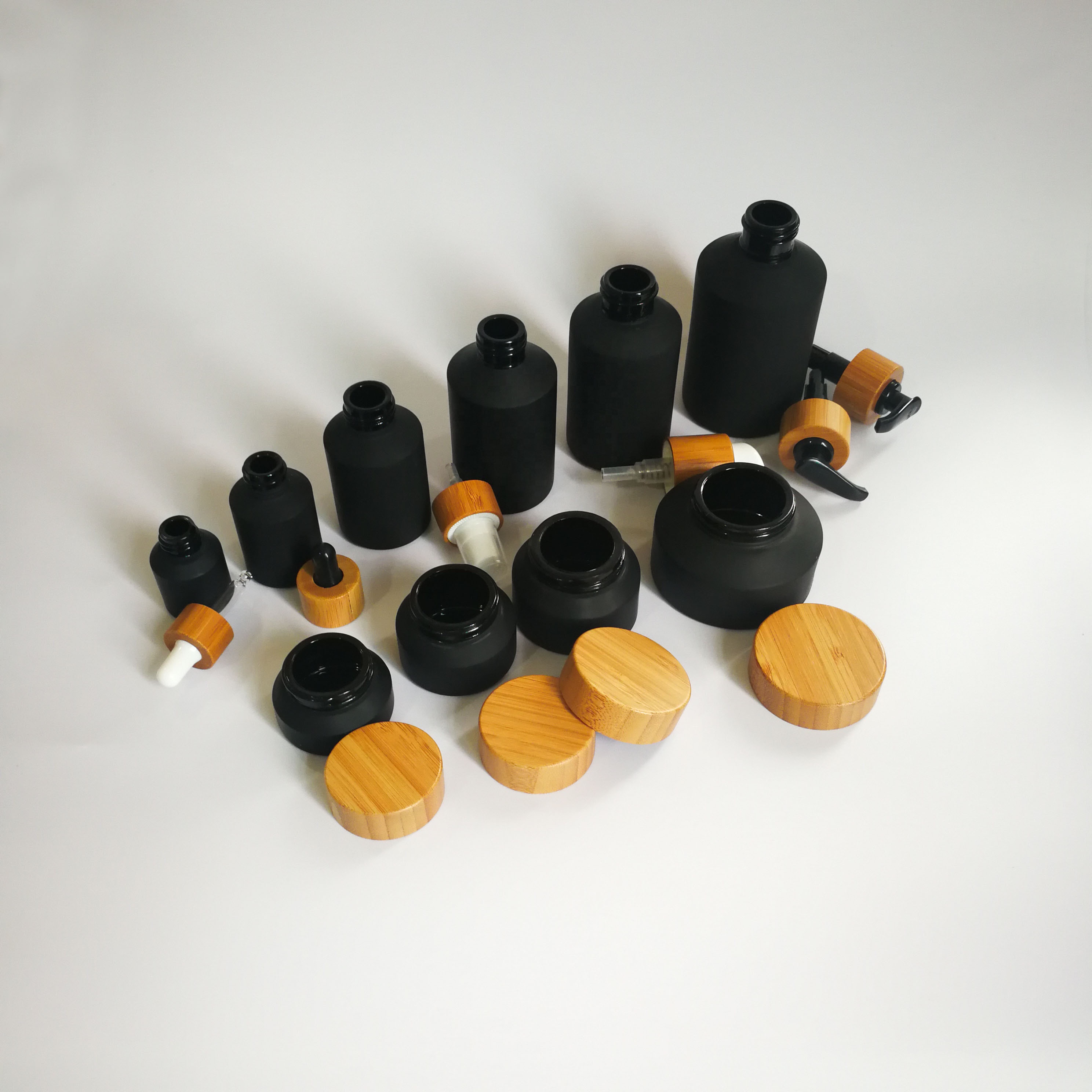 Cosmetic packaging slant shoulder matte black skin care set black glass bottle with bamboo dropper and bamboo cap jar