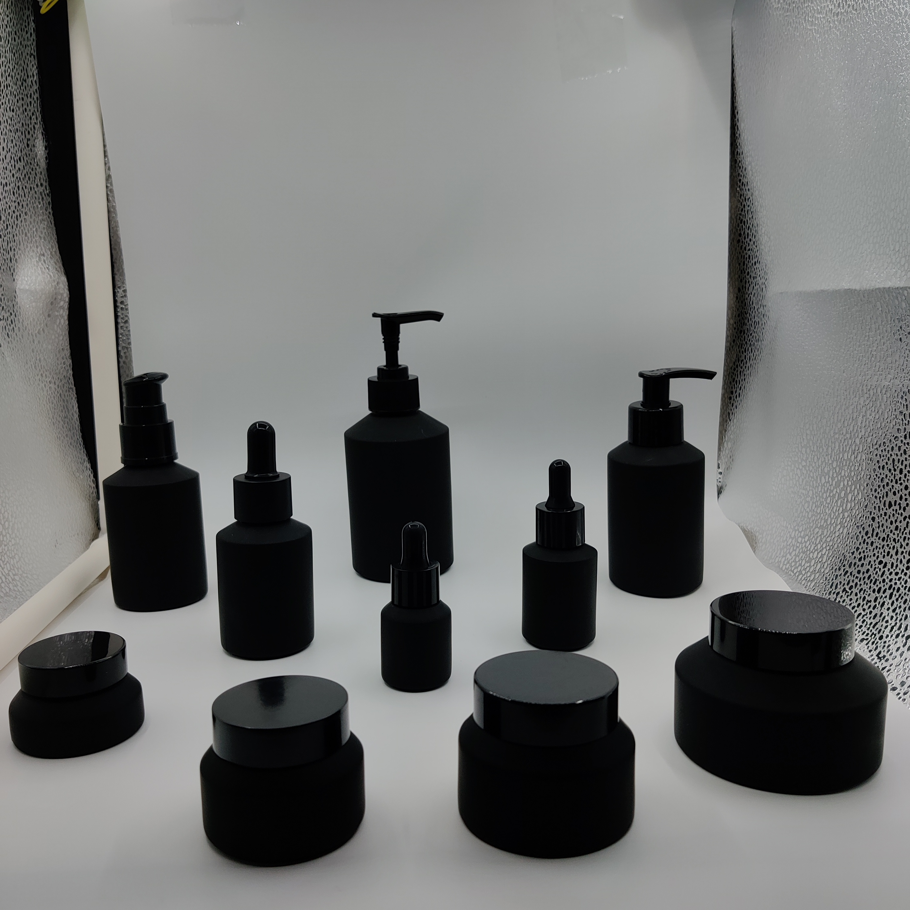 Cosmetic packaging slant shoulder matte black skin care set glass bottle cosmetic products with black dropper and jar with lid