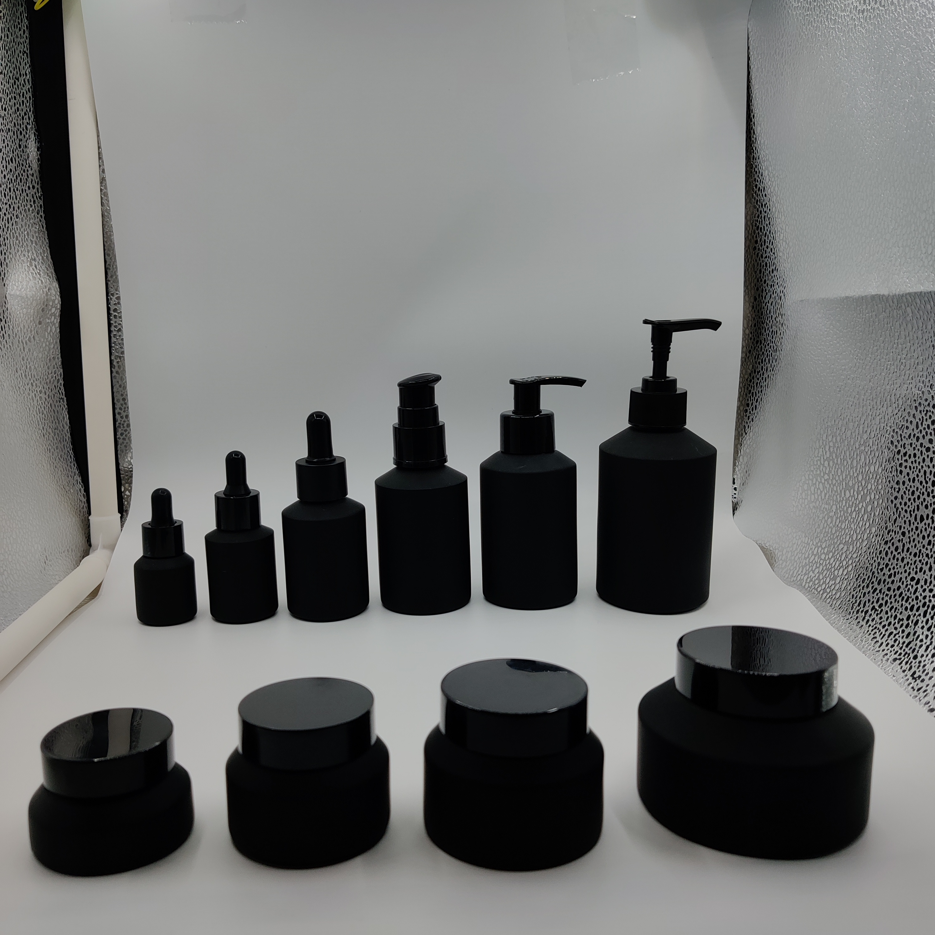 Cosmetic packaging slant shoulder matte black skin care set glass bottle cosmetic products with black dropper and jar with lid
