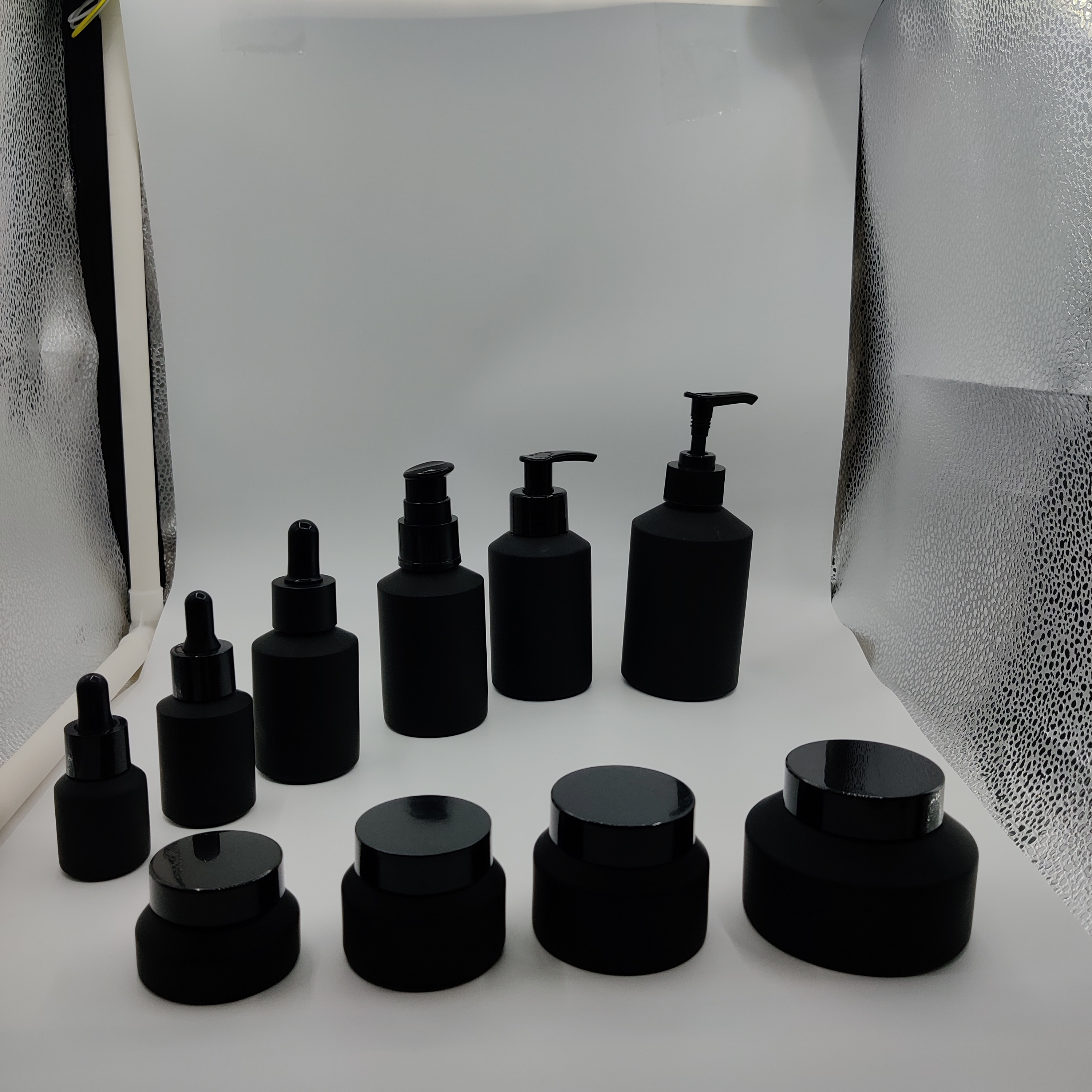 Cosmetic packaging slant shoulder matte black skin care set glass bottle cosmetic products with black dropper and jar with lid
