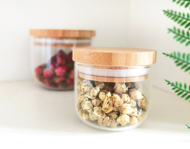 Delicate round bottom small glass jar with bamboo cover