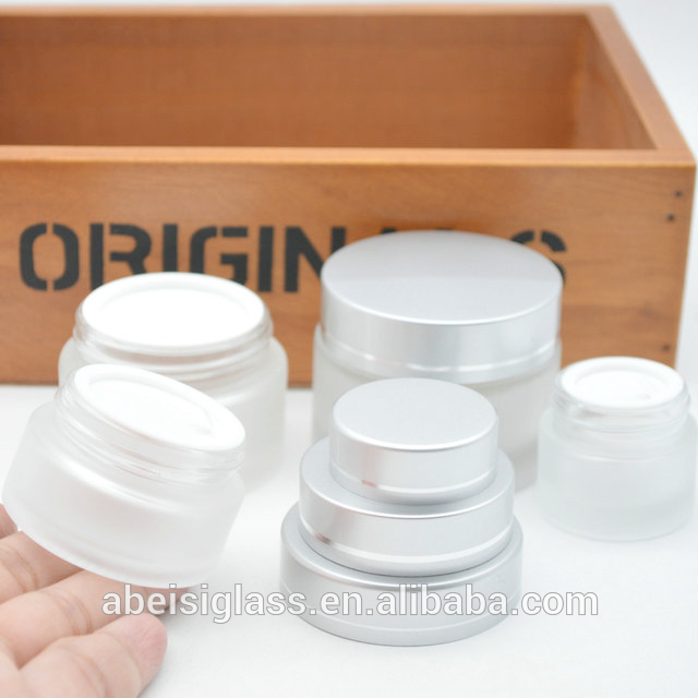 Empty frosted cosmetic glass jar with silver cap for eye cream and face cream