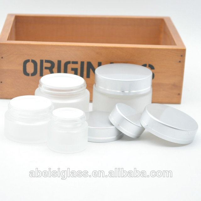 Empty frosted cosmetic glass jar with silver cap for eye cream and face cream