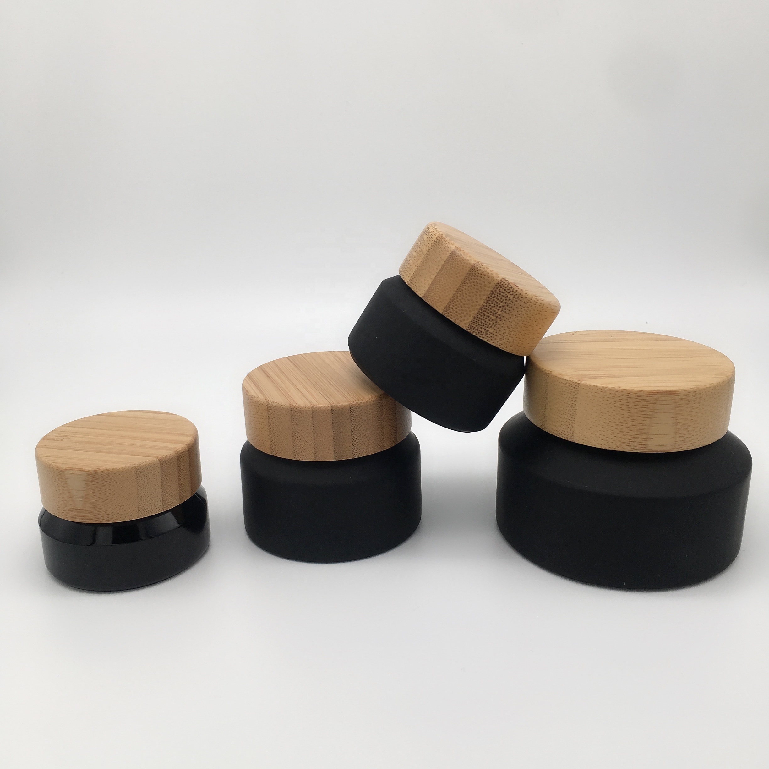 Factory hot sell cosmetic packaging frosted black glass bottle and jar with bamboo lid
