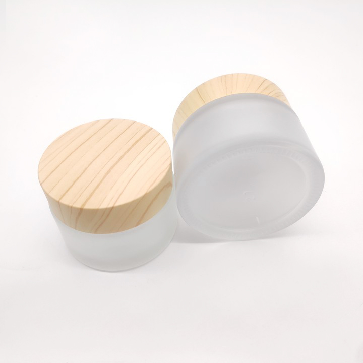 Factory manufactures frosted glass bottles for cosmetic packaging and clear face cream bottles with wood grain cover