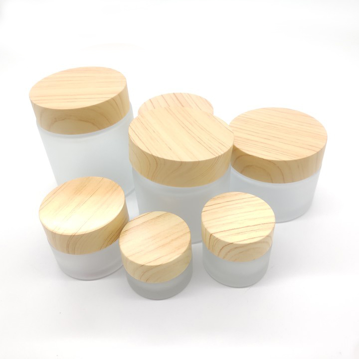 Factory manufactures frosted glass bottles for cosmetic packaging and clear face cream bottles with wood grain cover