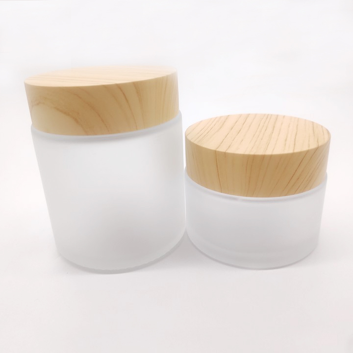 Factory manufactures frosted glass bottles for cosmetic packaging and clear face cream bottles with wood grain cover
