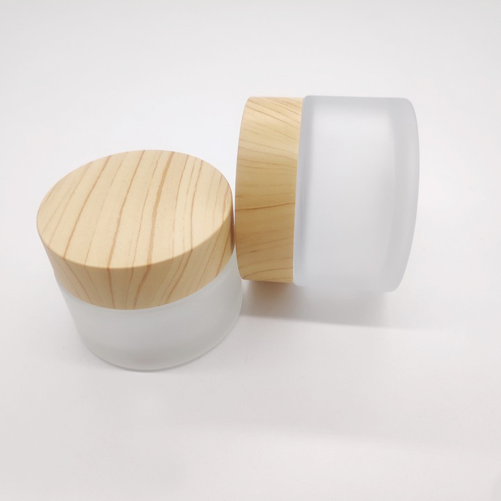 Factory manufactures frosted glass bottles for cosmetic packaging and clear face cream bottles with wood grain cover