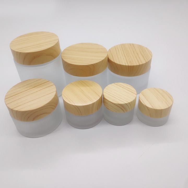 Factory manufactures frosted glass bottles for cosmetic packaging and clear face cream bottles with wood grain cover