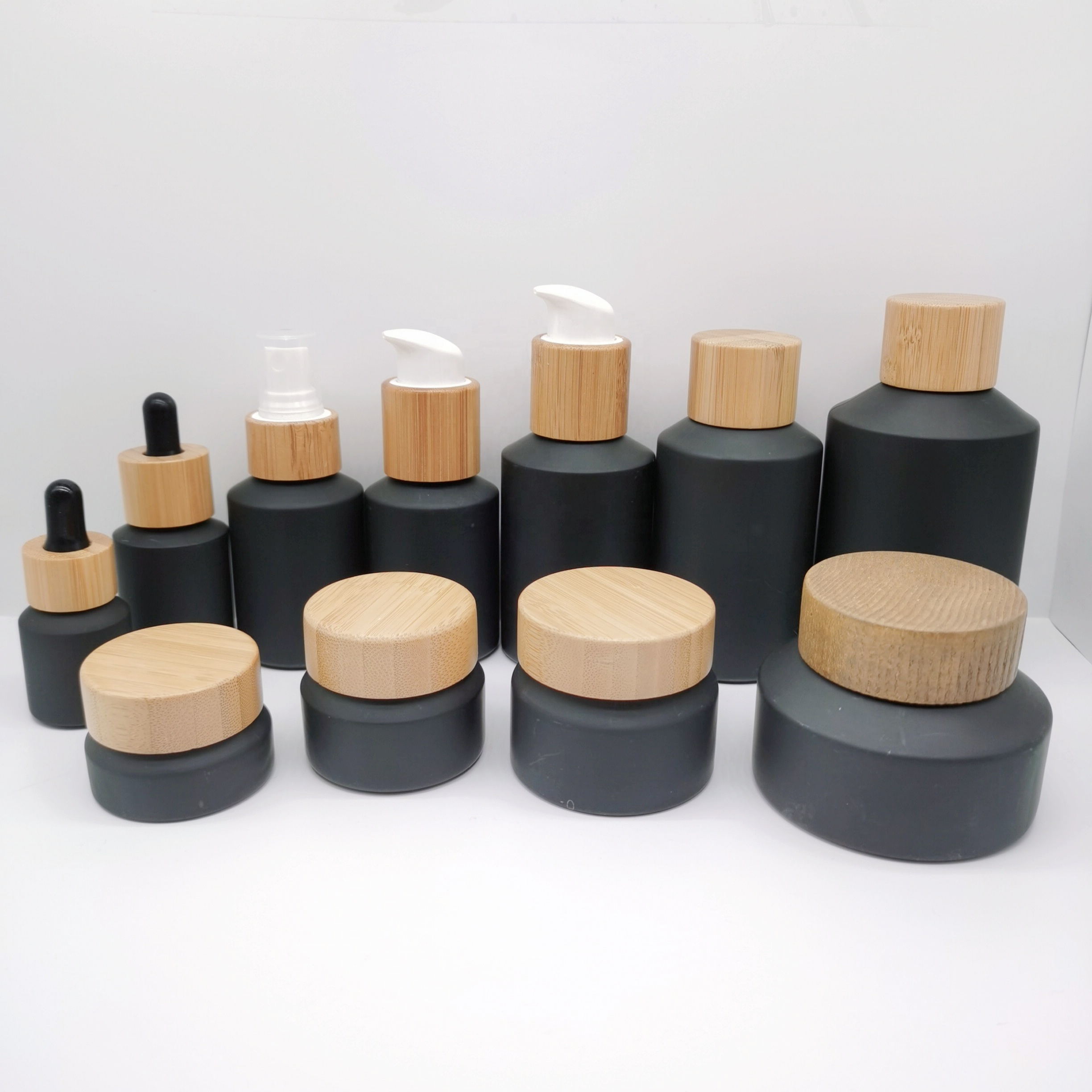 Factory production cosmetic glass bottles packaging slant shoulder matte black glass bottle and jar with bamboo lid series