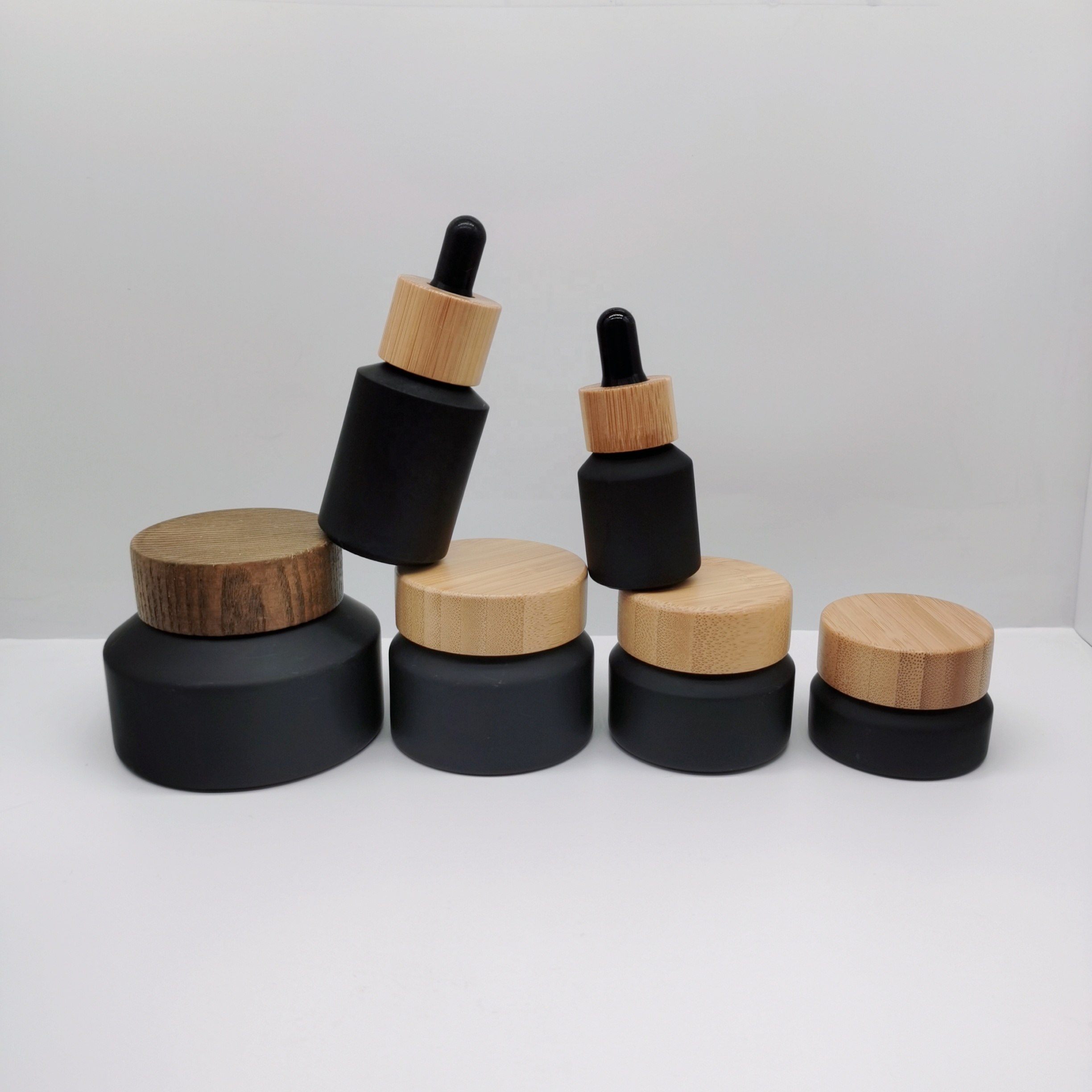 Factory production cosmetic glass bottles packaging slant shoulder matte black glass bottle and jar with bamboo lid series