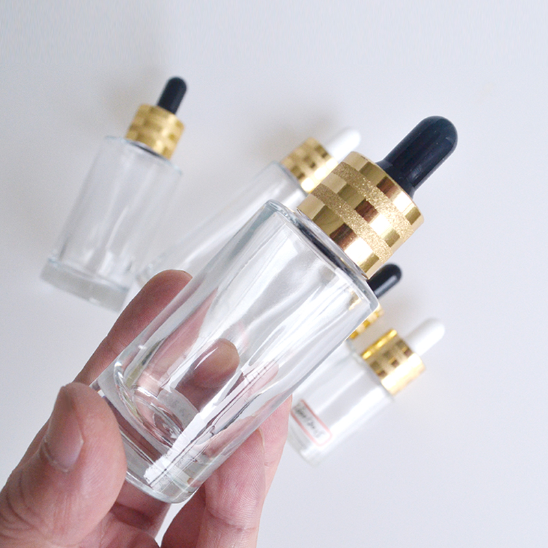 Hot sale luxury 30ml 50ml 60ml 100ml clear flat shoulder cosmetic beauty essential oil glass dropper bottle with gold cap