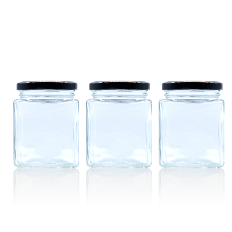 Square glass honey jar with black metal lid.