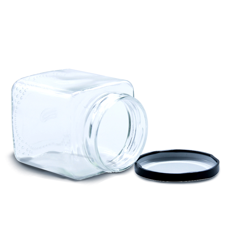 Square glass honey jar with black metal lid.